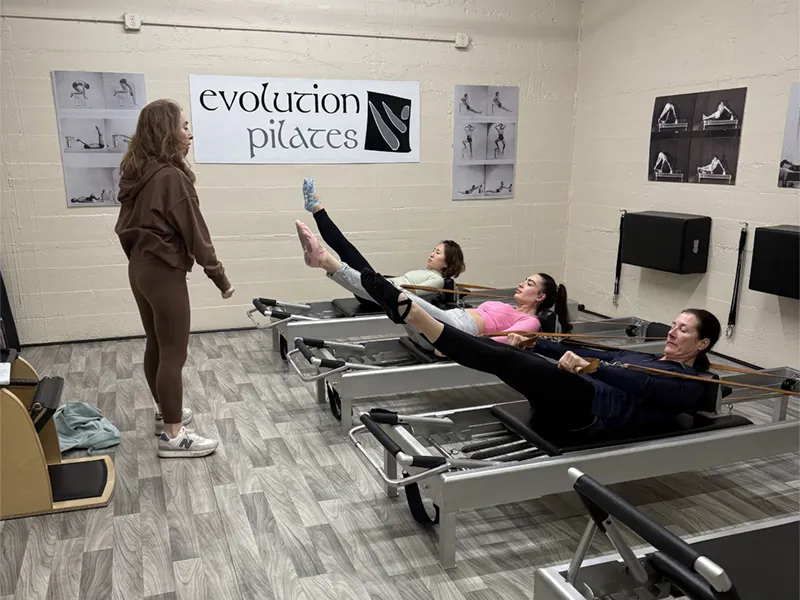 A group of women from Manhasset NY taking a reformer class at Evolution Pilates