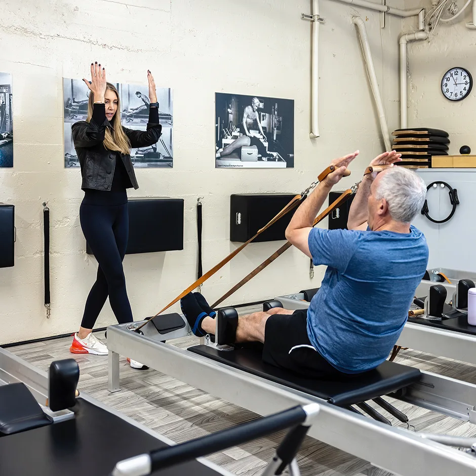 Male senior client working on the reformer during a Pilates class